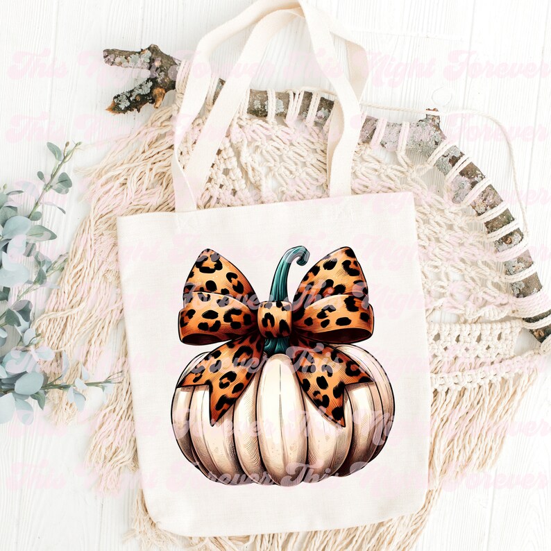 May include: A white tote bag with a brown and orange leopard print pumpkin with a green stem and a brown and orange leopard print bow on top.