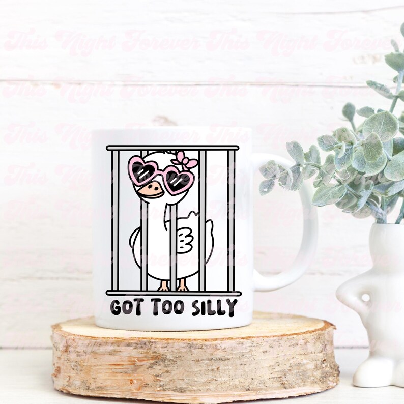 May include: White ceramic mug with a cartoon illustration of a goose wearing pink heart-shaped sunglasses and a pink bow, inside a cage. The text "GOT TOO SILLY" is printed below the image.