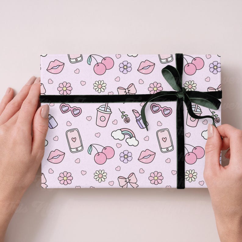 May include: Pink and white gift wrap with a repeating pattern of cherries, lips, hearts, flowers, rainbows, cell phones, sunglasses, and lipstick. The gift is wrapped with a black ribbon.