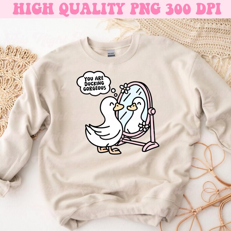 K&ouml;nnte beinhalten: Ein beiger Pullover mit einem Aufdruck eines Entchens, das in einen Spiegel schaut. Die Gedankenblase &uuml;ber dem Entchen sagt "You are ducking gorgeous".