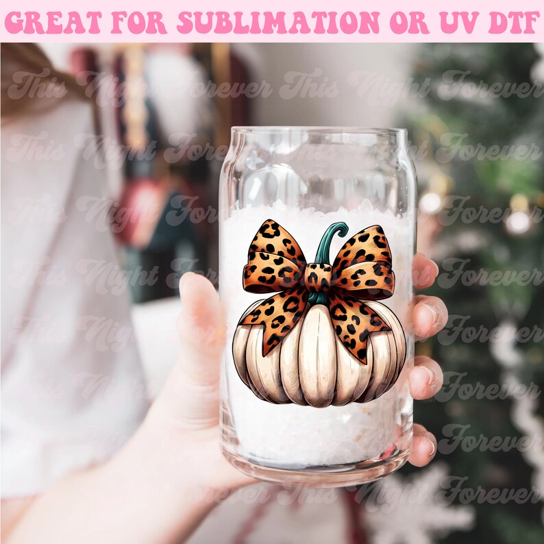 May include: A white pumpkin with a brown and orange leopard print bow. The pumpkin is on a clear glass mug.