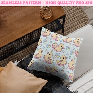 May include: A square pillow with a light blue background featuring a repeating pattern of yellow rubber ducks with pink accents, colorful beach balls, and stars. The pillow is on a neutral-toned surface. Text at the top reads "SEAMLESS PATTERN - HIGH QUALITY PNG JPG".