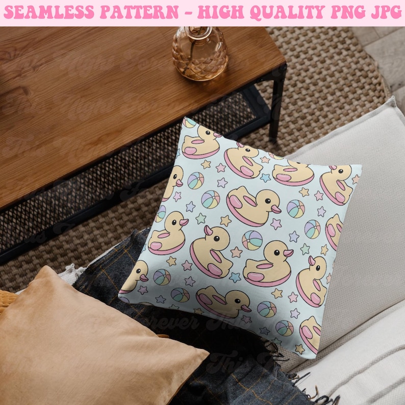 May include: A square pillow with a light blue background featuring a repeating pattern of yellow rubber ducks with pink accents, colorful beach balls, and stars. The pillow is on a neutral-toned surface. Text at the top reads "SEAMLESS PATTERN - HIGH QUALITY PNG JPG".