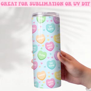 May include: A light blue stainless steel tumbler with a pattern of colorful candy hearts. The hearts have various messages on them, including "miss you", "be mine", "cutie", "sweet", "true love", and "kiss me".
