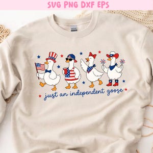 以下が含まれることがあります： ベージュ色のスウェットシャツ。愛国的な服装をした4羽のガチョウの気まぐれなデザインが特徴です。各ガチョウは帽子、サングラス、バンダナなどのアクセサリーを身に着け、アメリカ国旗やスパークラーなどのアイテムを持っています。「just an independent goose」の文字が下にあります。