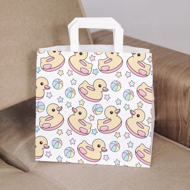 May include: White paper gift bag with a repeating pattern of yellow ducks, pink inner tubes, pastel-colored beach balls, and stars. The bag has a white handle and is suitable for gifts.