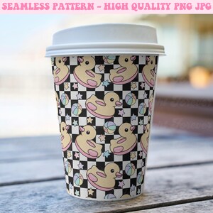 May include: A disposable coffee cup with a white lid. The cup features a repeating pattern of yellow rubber ducks with pink inner tubes, pastel-colored beach balls, and stars on a black and white checkered background. The text "SEAMLESS PATTERN - HIGH QUALITY PNG JPG" is at the top.