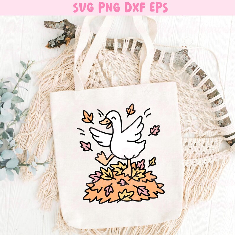 May include: A white canvas tote bag featuring a cartoon goose running through a pile of autumn leaves. The design includes the text "SVG PNG DXF EPS" at the top. The goose is depicted with its wings spread and a happy expression.