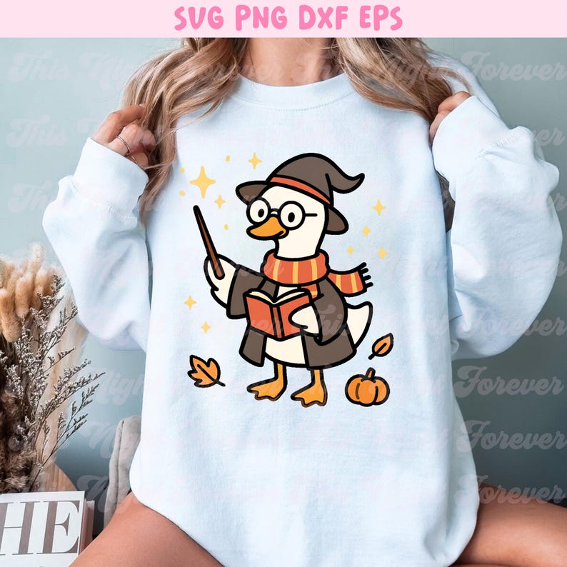 May include: White sweatshirt featuring a cartoon duck dressed as a wizard, wearing a hat, glasses, and scarf. The duck holds a wand and a book, with autumn leaves and a pumpkin nearby. Text at the top reads "SVG PNG DXF EPS".