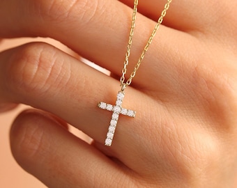 May include: A gold chain necklace with a small diamond cross pendant.