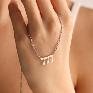 May include: A silver chain necklace with a pendant featuring the Hebrew letters 'Chai' (meaning 'life').