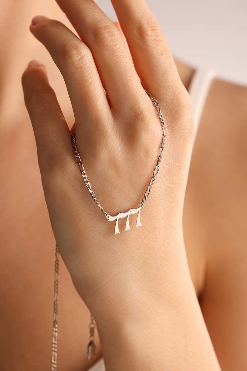May include: A silver chain necklace with a pendant featuring the Hebrew letters 'Chai' (meaning 'life').
