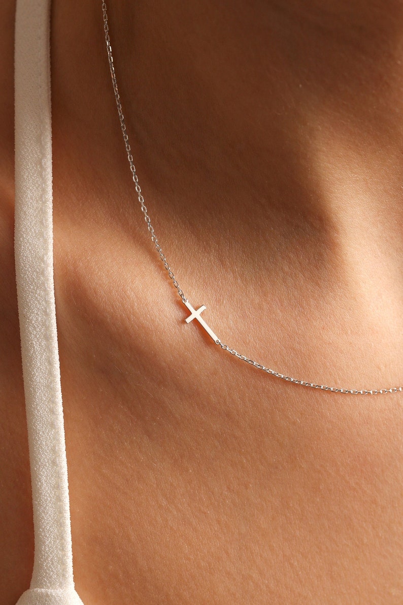 May include: A silver chain necklace with a small silver cross pendant.