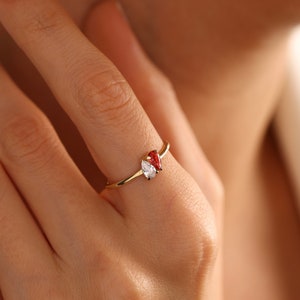 May include: A gold ring with two pear-shaped gemstones. One gemstone is clear and the other is red.