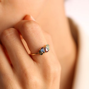 May include: A gold ring with three oval-shaped gemstones. The gemstones are blue, green, and red.