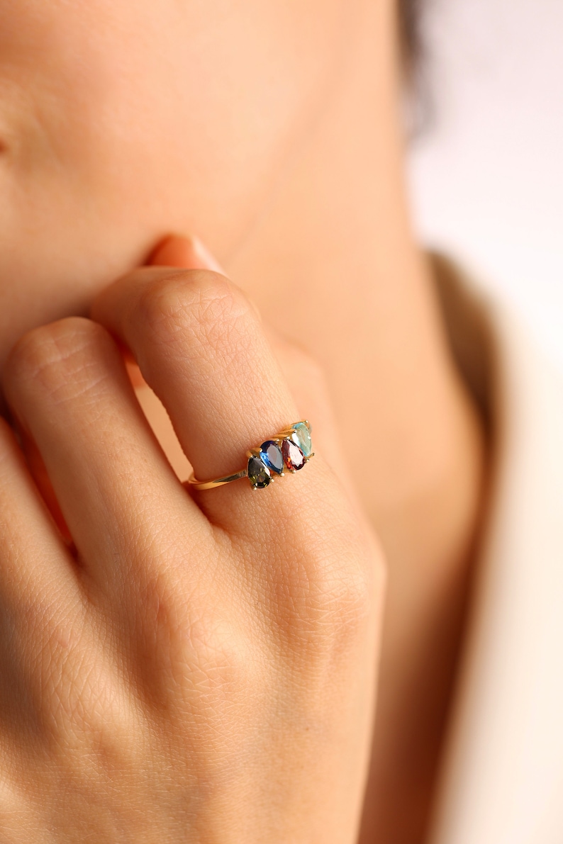 May include: A gold ring with three oval-shaped gemstones. The gemstones are blue, green, and red.