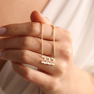 May include: A gold chain necklace with a pendant featuring the number 222 in a gothic font.