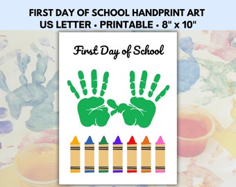 May include: Printable first day of school handprint art with the text "First Day of School" and two green handprints. The art also includes a row of eight crayons in various colors.