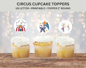 May include: Three cupcakes with white frosting topped with round, colourful circus-themed cupcake toppers. The toppers feature a red and white striped tent, a clown juggling balls, and a man on a unicycle with a woman on a trapeze.