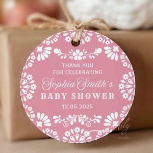 May include: A circular pink baby shower gift tag with white floral and decorative patterns. The tag says "Thank You For Celebrating Sophia Smith's Baby Shower 12.05.2025". It is attached with twine.