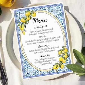 Könnte beinhalten: Eine blaue und weiße gekachelte Speisekarte mit einem Zitronenzweig-Design. Die Speisekarte listet Vorspeisen, Hauptgerichte, Desserts und Getränke auf. Der Text lautet: "Menü, Vorspeisen, Caprese-Salat, Bruschetta al Pomodoro und Zucchini-Fritters, Hauptgericht, Spaghetti alle Vongole mit frischen Muscheln und Risotto alla Pescatora mit frischen Meeresfrüchten, Desserts, Zitronen-Ricotta-Käsekuchen, Delizia al Limone und Torta Caprese, Getränke, San Pellegrino Limonata, Eistee mit Zitrusfrüchten, Frische Fruchtsmoothies."