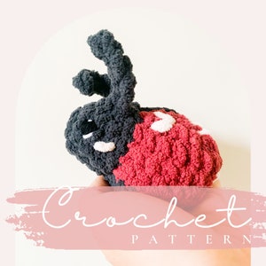 May include: Crochet pattern for a ladybug amigurumi toy. The ladybug is red with black spots and has black antennae. The toy is being held in a hand.