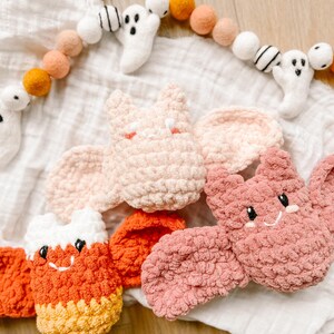 May include: Three crocheted Halloween decorations: a pink bat, a pink and white candy cane, and an orange and yellow candy cane.