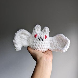May include: White crocheted bat plush toy with red eyes and a black "W" on its face.