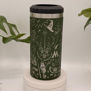 May include: A green insulated drinks holder with a black top, decorated with etched images of a stag, lightning bolt, and other symbols. The words "Expecto Patronum" and "Lumos" are etched on the holder.