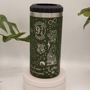 May include: Green insulated can cooler with a black top. The cooler is decorated with white illustrations of the Hogwarts Express logo, glasses, a lightning bolt, an owl, and the word "Lumos". The text "Hogwarts Express" is also visible.