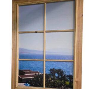 Pode incluir: Uma janela com moldura de madeira clara, com vista para o mar e o céu azul. A paisagem inclui água, montanhas e palmeiras, criando uma cena serena.