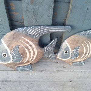 May include: Two wooden fish wall decor with a blue and white painted design. The fish are carved in a realistic style and have a 3D effect.