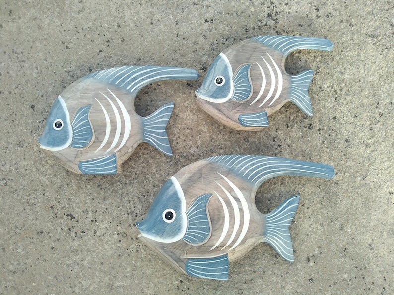 May include: Three wooden fish wall decor in shades of brown and blue with white accents. The fish are carved with details and have a distressed finish.