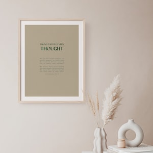 May include: A framed print with a beige background and green text. The text reads "Taking captive every thought" and includes a Bible verse from 2 Corinthians 10:4-5.