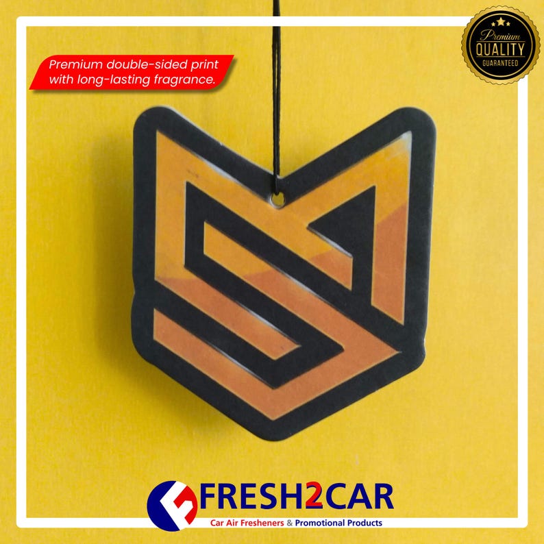 Pu&ograve; includere: Un deodorante per auto con un design geometrico nero e arancione, appeso su uno sfondo giallo. Il testo "Premium double-sided print with long-lasting fragrance" &egrave; visibile. Il logo "FRESH2CAR" &egrave; in basso.