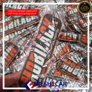 Pu&ograve; includere: Una collezione di profumatori per auto in confezioni trasparenti. I profumatori rettangolari hanno un design nero e arancione con la scritta "UBILACK" e altro testo. L'immagine include anche la scritta "FRESH2CAR".