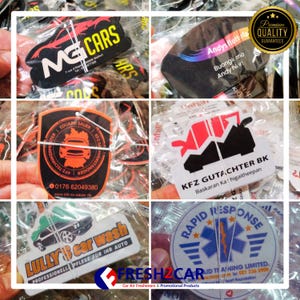 May include: Assorted car air fresheners with various designs and text. Includes a black and red car-shaped freshener with "MG CARS" and a black freshener with "Andys flott Ha". Other designs include "EDUARD SAUER", "KFZ GUTACHTER BK", "LULLY'S car wash", and "RAPID RESPONSE".