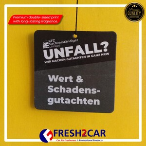 May include: A black car air freshener with white text that reads "UNFALL?" and "Wert & Schadensgutachten" on a yellow background. The freshener has a premium quality seal and the text "FRESH2CAR" at the bottom.