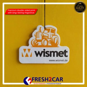 May include: White car air freshener with an orange tractor design, the brand name "wismet" is printed below the tractor. The text "Premium double-sided print with long-lasting fragrance" is visible. The product is from FRESH2CAR.