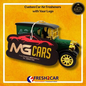 Pu&ograve; includere: Un modello di auto d'epoca verde e oro con un profumatore per auto personalizzato con la scritta "MG CARS" e l'indirizzo. Il profumatore per auto &egrave; nero con una grafica di auto rossa. L'immagine include anche il testo "Custom Car Air Fresheners with Your Logo."