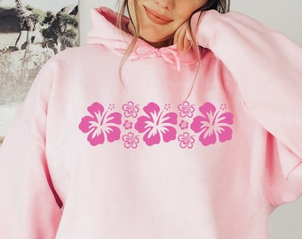 May include: A pink hoodie with a row of pink hibiscus flowers printed across the chest.