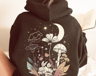 May include: A black hooded sweatshirt with a graphic print of flowers, mushrooms, and a crescent moon. The graphic is in a minimalist style with gold accents.