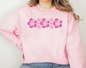 May include: A pink sweatshirt with a row of pink hibiscus flowers printed across the chest.