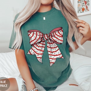 May include: A teal green t-shirt with a white and red bow with sprinkles on it.