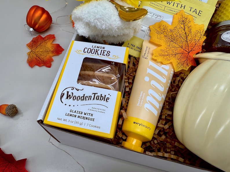 May include: A gift box with fall-themed items. It includes a box of lemon cookies, a tube of hand cream, a pumpkin-shaped container, and decorative fall leaves. The cookies are glazed with lemon meringue and weigh 3 oz (85 g).