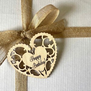 May include: A brown gift box with a brown burlap ribbon and bow. A wooden heart-shaped tag with the text "Happy Birthday!" is attached to the ribbon.