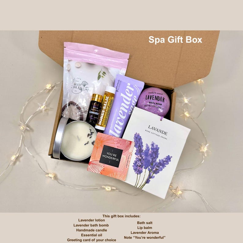 May include: A spa gift box filled with lavender-scented products. The box contains a candle, bath bomb, lotion, lip balm, essential oil, bath salts, and a greeting card. The card has a lavender flower illustration and the text "You're Wonderful".