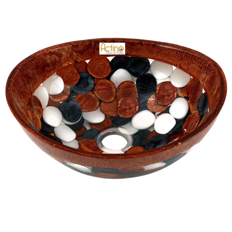 May include: A brown, oval-shaped sink with a white, black, and brown pebble design. The sink has a drain hole in the center.