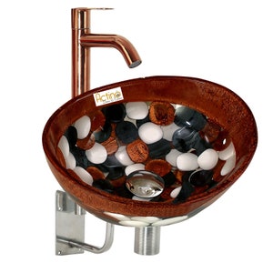 May include: A brown and white glass vessel sink with a copper faucet and a silver drain. The sink is decorated with a mosaic of white, black, and brown stones.