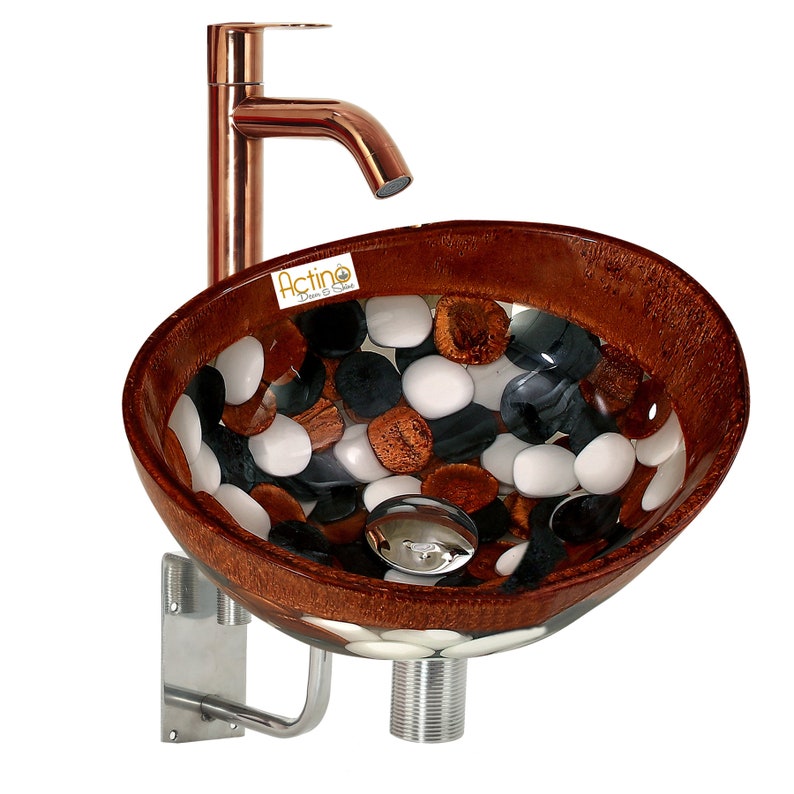 May include: A brown and white glass vessel sink with a copper faucet and a silver drain. The sink is decorated with a mosaic of white, black, and brown stones.